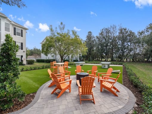 an outdoor patio with orange chairs and a fire pit
