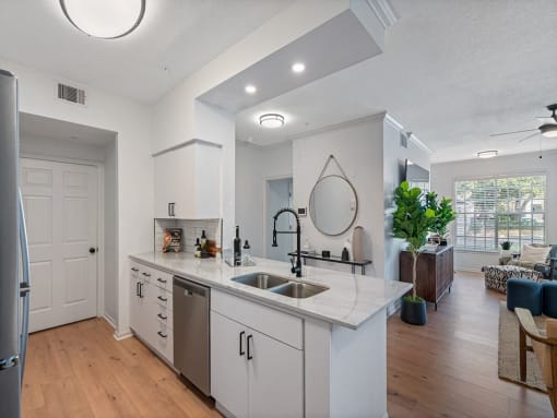 an open kitchen and living room with white cabinets and a sink