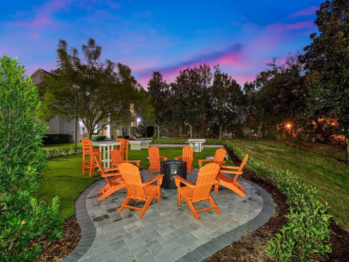 a patio with orange chairs and a fire pit