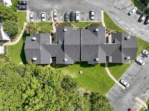 A large building with a grey roof is surrounded by a grassy area and a parking lot at Sedgefield Square Apartments, Greensboro, North Carolina