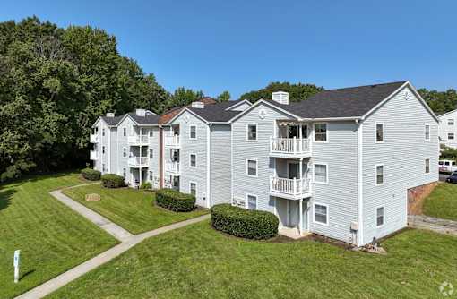 A large white apartment building with a green lawn in front at Sedgefield Square Apartments, Greensboro, NC, 27407