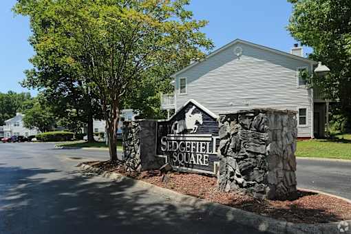 A stone sign that says Sleepyfield Square stands in front of a house at Sedgefield Square Apartments, Greensboro, NC