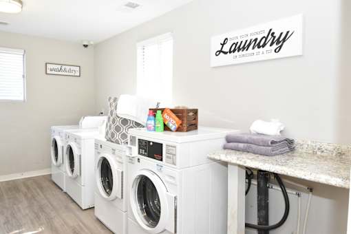A row of white front load washing machines in a laundry room at Sedgefield Square Apartments, Greensboro