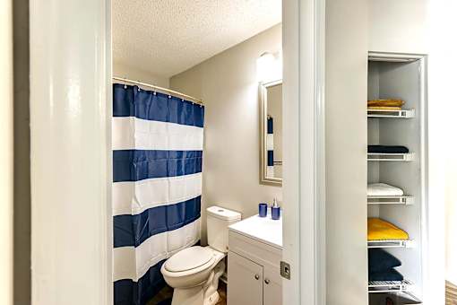A bathroom with a blue and white striped shower curtain at Sedgefield Square Apartments, Greensboro, NC
