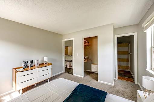 A room with a white bed and a wooden dresser at Sedgefield Square Apartments, Greensboro, North Carolina