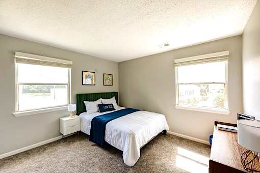A bedroom with a bed, nightstand, and window at Sedgefield Square Apartments, Greensboro, NC