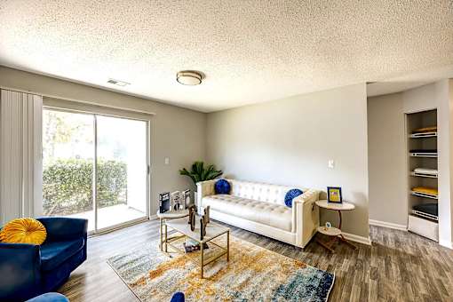 A living room with a white couch and a blue chair at Sedgefield Square Apartments, Greensboro, 27407