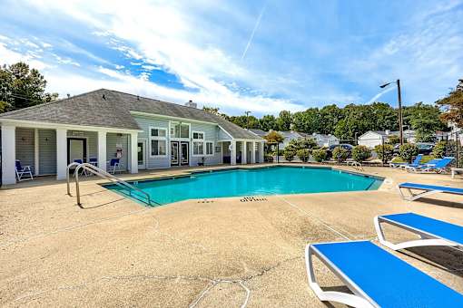 A pool area with a small building and lounge chairs at Sedgefield Square Apartments, Greensboro