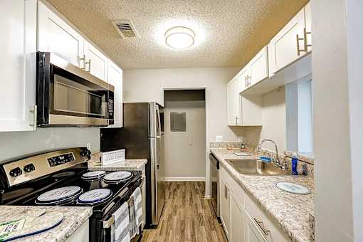 A kitchen with a black stove top oven and a black microwave above it at Sedgefield Square Apartments, North Carolina, 27407