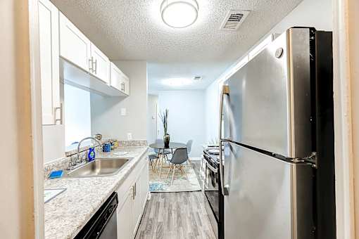 A kitchen with a black refrigerator and white cabinets at Sedgefield Square Apartments, North Carolina, 27407