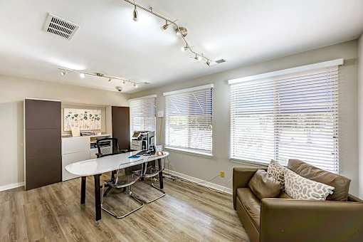 A room with a brown couch and a white desk at Sedgefield Square Apartments, North Carolina