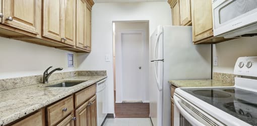 a kitchen with wooden cabinets and white appliances at The Ivanhoe Apartments, Hackensack, NJ, 07601