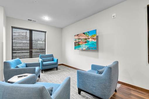A living room with blue chairs and a television.