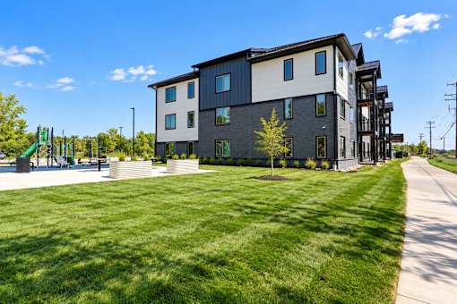 A modern apartment building with a grassy area in front.