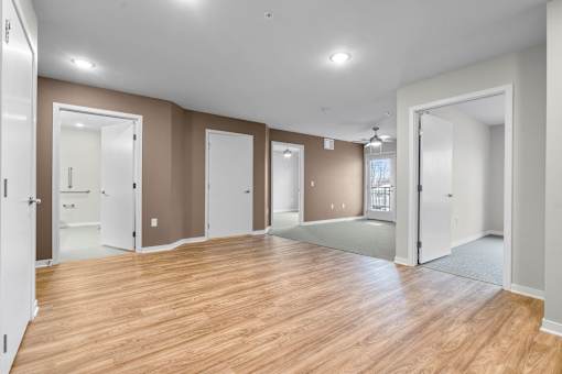 A large dining and living room with wooden floors and carpet with white trim.