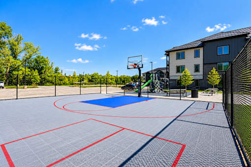 A basketball court with a blue and red surface and a basketball hoop.