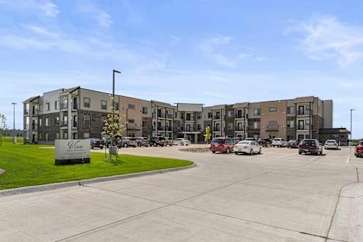 an empty parking lot with an apartment building in the background