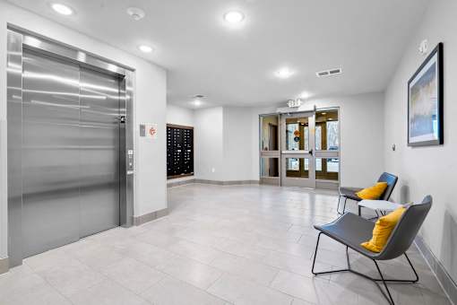 A spacious hallway with a chair and a painting on the wall.