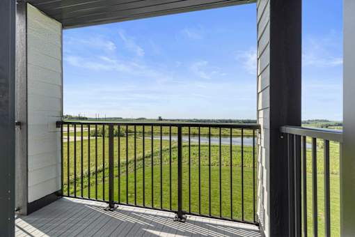 a balcony with a view of a field and a blue sky