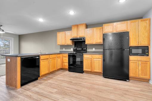 A kitchen with black appliances and wooden cabinets.