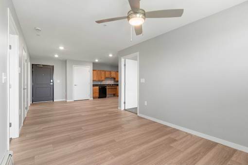 a living room with a ceiling fan and a door to a kitchen
