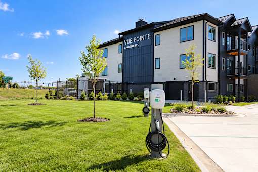 A charging station for electric vehicles is in front of a building with the sign "Vue Pointe Apartments.".