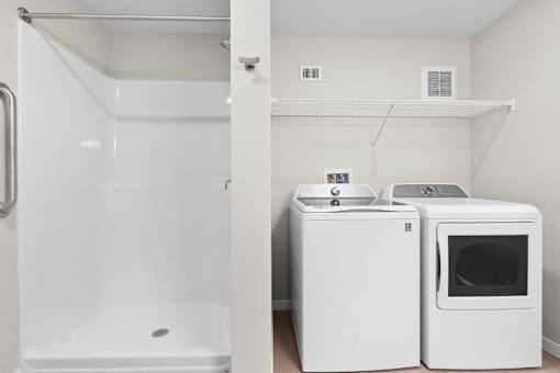 A white bathroom with a shower and a washer and dryer
