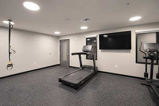 A spacious room with a treadmill, exercise bike, and television.