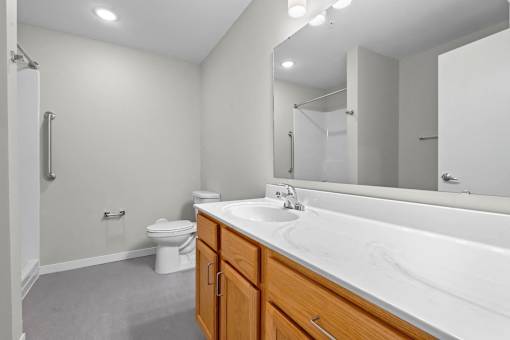 A bathroom with a toilet, sink, and mirror.