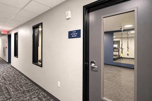 A hallway leading to a fitness room.