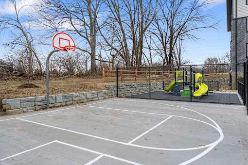 A basketball court with a basketball hoop and a playground with a slide.