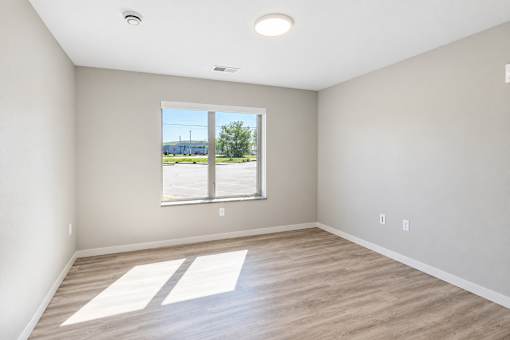 A room with a large window and wooden flooring.