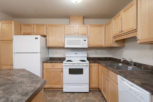 A kitchen with a white refrigerator, white oven, and wooden cabinets.