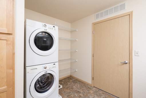 Stacked washing & dryer machine in a laundry room.