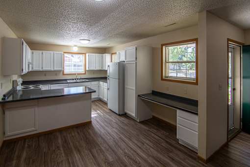 A kitchen with white cabinets and a black counter top.
