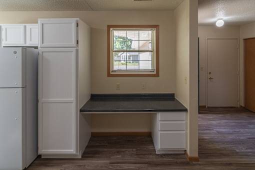 A kitchen with a white fridge, a window, and a bench.