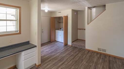 A room with a wooden floor and a window on the left side.