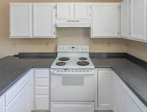 A white stove and oven in a kitchen with white cabinets.