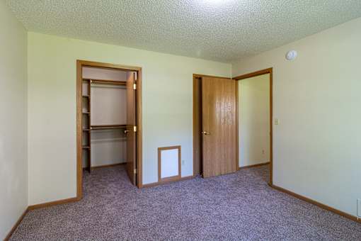 A room with a carpeted floor and two doors.