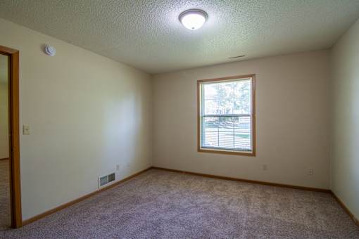A room with a window and carpeted floor.