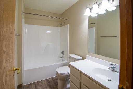 A white bathroom with a toilet, sink, and shower.
