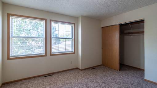 A room with two windows and a closet.