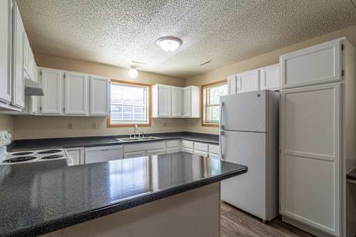 A kitchen with white cabinets and a black counter top.