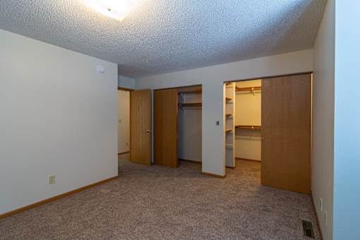 A room with a carpeted floor and a washer and dryer in the corner.