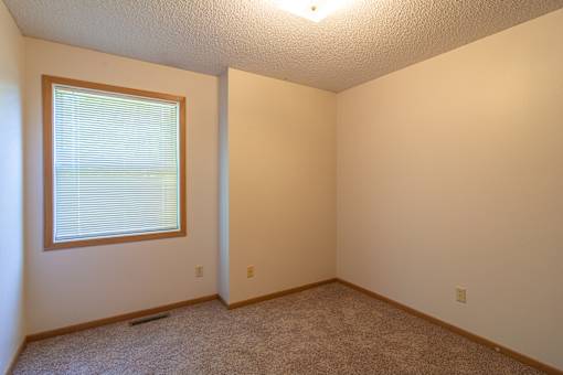 A room with a window and carpeted floor.