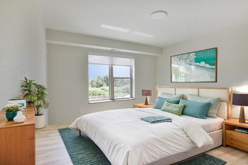 A bedroom with a large bed, a nightstand, and a painting on the wall.
