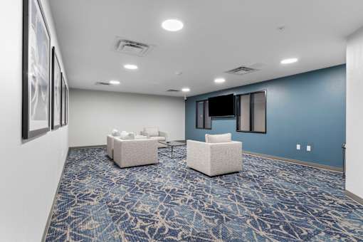 a community room with couches and chairs and a television