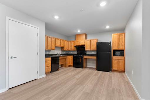 an empty kitchen with wooden cabinets and a black refrigerator