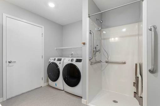 a washer and dryer in a laundry room with a shower and a door