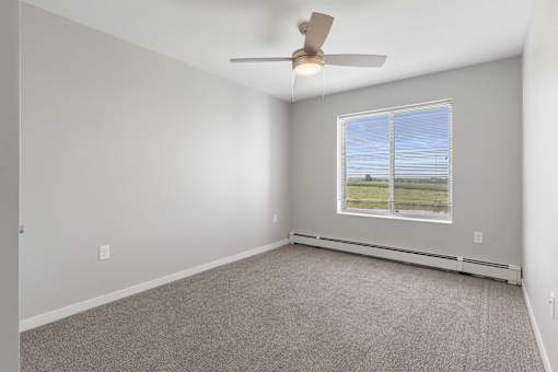 an empty living room with a ceiling fan and a window